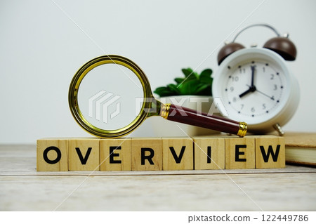 Magnifying glass and alarm clock with wooden blocks alphabet letters OVERVIEW text message on wooden background Magnifying glass and alarm clock with wooden blocks alphabet letters OVERVIEW text message on wooden background 122449786