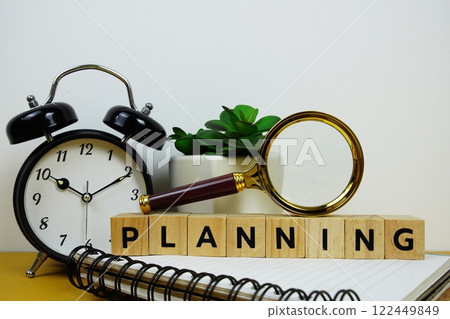 Magnifying glass and alarm clock with wooden blocks alphabet letters PLANNING text message on yellow background Magnifying glass and alarm clock with wooden blocks alphabet letters PLANNING text message on yellow background 122449849