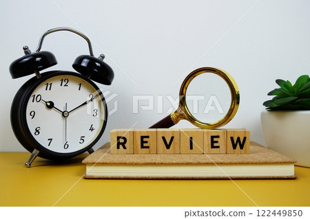 Magnifying glass and alarm clock with wooden blocks alphabet letters REVIEW text message on yellow background Magnifying glass and alarm clock with wooden blocks alphabet letters REVIEW text message on yellow background 122449850