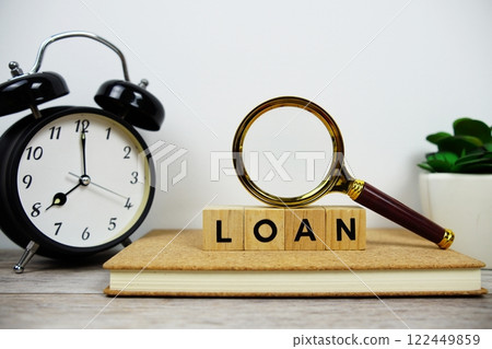 Magnifying glass and alarm clock with wooden blocks alphabet letters LOAN text message on wooden background Magnifying glass and alarm clock with wooden blocks alphabet letters LOAN text message on wooden background 122449859