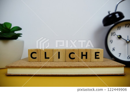 Alarm clock with wooden blocks alphabet letters CLICHE on yellow background Alarm clock with wooden blocks alphabet letters CLICHE on yellow background 122449906