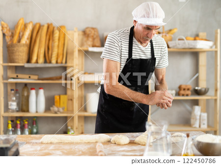 Elderly man baker making pieces of dough Elderly man baker making pieces of dough 122450786