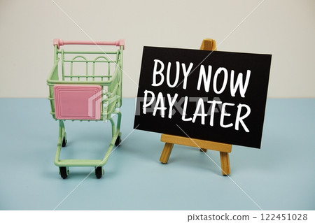 Buy Now Pay Later text message and trolley shopping cart on blue background 122451028