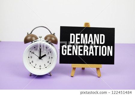 Demand Generation text on paper card with alarm clock on purple background 122451484