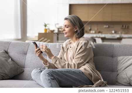Happy mature female enjoy virtual communication on cell at home Happy mature female enjoy virtual communication on cell at home 122451553