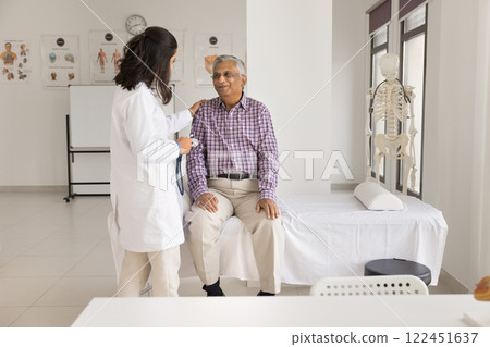 Smiling doctor put hand on aged patient shoulder after checkup 122451637