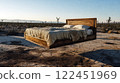 Wooden bed floating over dry cracked earth in desert landscape at sunrise 122451969