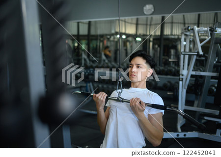 Athletic woman workout with lat pulldown cable machine to build back and shoulder muscles Athletic woman workout with lat pulldown cable machine to build back and shoulder muscles 122452041