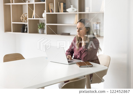 Businesslady using her laptop seated at desk in conference room Businesslady using her laptop seated at desk in conference room 122452867
