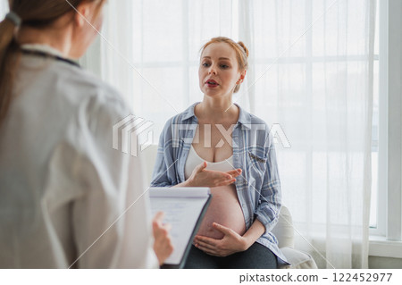 Female doctor examining pregnant woman in doctor office. Pregnant girl patient have consultation in hospital. Gynecologist doctor consulting patient about pregnancy. Visit to doctor medical checkup 122452977