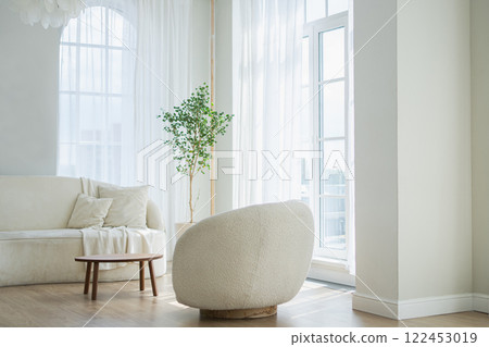 Stylish loft bedroom interior. Spacious design apartment with light walls large windows white couch sofa and armchair. Clean modern decoration with elegant furniture in minimalist Scandinavian style 122453019