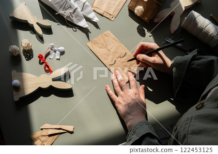 DIY process of woman making candid Easter present paper bag bunny arrangement decor. Series of handmade craft paper gift idea instruction manual activity for children. Zero waste eco-friendly 122453125