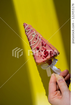 New look of trendy miniature ice cream cheesecake on stick in vibrant pink color on yellow background. Copy space mock up template sample for bakery mini dessert coffee shop. Cake to go takeaway sweet 122453176