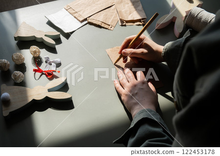 Step by step instruction of making handmade Easter gift bag rabbit bunny shaped sustainable materials decorations from craft paper. Female hands creating craft homemade present. Easter celebration Step by step instruction of making handmade Easter gift bag rabbit bunny shaped sustainable materials decorations from craft paper. Female hands creating craft homemade present. Easter celebration 122453178