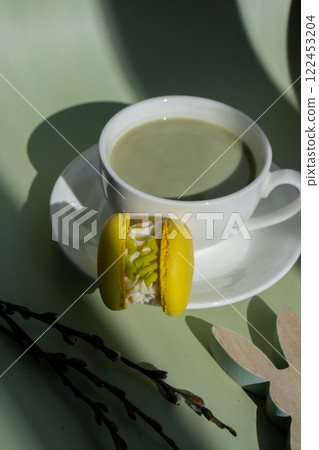 Green latte matcha with yellow macaron dessert and EASTER sustainable decoration. Concept of holiday breakfast morning tea drink. Cozy minimalist superfood vibrant colors healthy eating. Organic 122453204