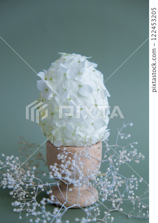 Easter egg made of white lilac spring flowers in pastel green background. Sustainable holiday minimalistic still life composition. Copy space template for invitation greeting card Easter egg made of white lilac spring flowers in pastel green background. Sustainable holiday minimalistic still life composition. Copy space template for invitation greeting card 122453205