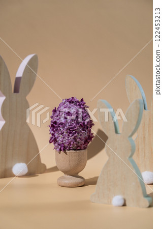 Creative Easter egg shape made of lilac spring petals flowers. Eco-friendly wooden bunnies decoration. Minimal holiday concept still life. Copy space greeting card Creative Easter egg shape made of lilac spring petals flowers. Eco-friendly wooden bunnies decoration. Minimal holiday concept still life. Copy space greeting card 122453213