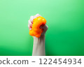Hand squeeze orange stress ball on green background. Positive thinking concept 122454934