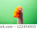 Hand squeeze orange stress ball on green background. Positive thinking concept 122454935