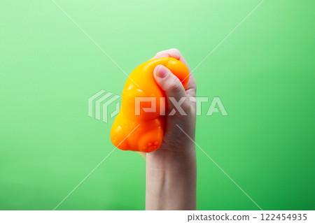 Hand squeeze orange stress ball on green background. Positive thinking concept Hand squeeze orange stress ball on green background. Positive thinking concept 122454935