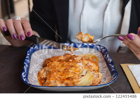 Cutting lasagna food on a plate in a close-up view. 122455486