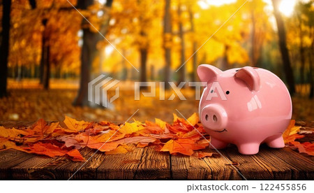 Piggy bank surrounded by colorful autumn leaves in a forest setting 122455856