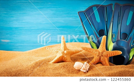 Flippers and starfish on sandy beach with blue background during daylight hours 122455860
