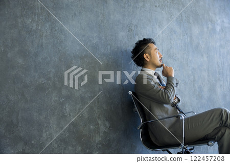 Man in suit sitting on chair Man in suit sitting on chair 122457208