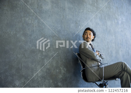 Man in suit sitting on chair 122457216