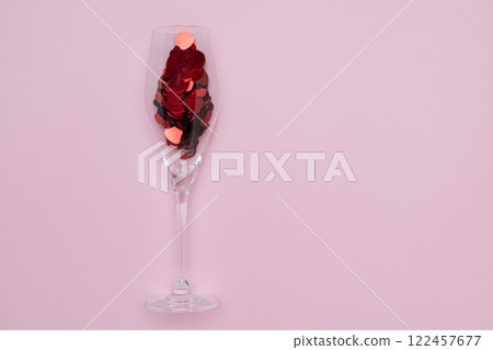 Creative representation of a wineglass filled with shimmering red sequins against a pastel pink backdrop. Ideal for themes of celebration, romance, minimalism, and modern aesthetics valentines 122457677