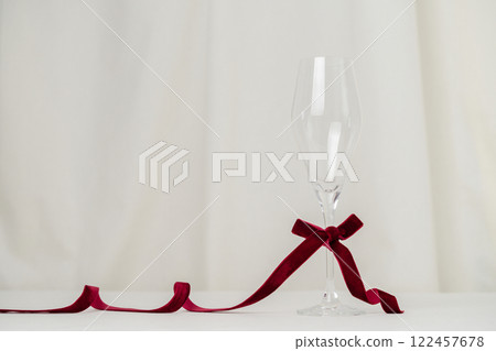 A minimalist and creative composition featuring a wine glass, red velvet ribbon on a soft cream background, representing elegance, Valentines celebration, and sophisticated design. 122457678