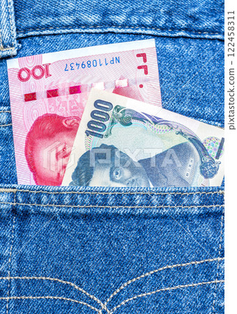 Chinese yuan and Japanese yen banknotes sticking out of the jeans pocket 122458311