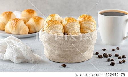 A cozy basket holds flaky croissants with cream, paired with a steaming cup of coffee for a delightful breakfast 122459479