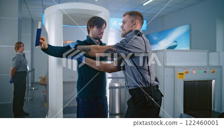 Man Passes Through Metal Detector Scanner. Security Officer Checks Documents, Inspects Passenger 122460001