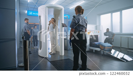 Woman Walks Through Metal Detector Gates. Security Officer Checks Passenger and Documents Woman Walks Through Metal Detector Gates. Security Officer Checks Passenger and Documents 122460032