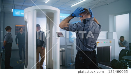 Elderly Man Walks Through Metal Detector Gates. Security Officer Checks Passenger for Plane Flight Elderly Man Walks Through Metal Detector Gates. Security Officer Checks Passenger for Plane Flight 122460065