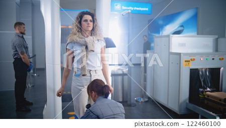 Woman Walks Through Metal Detector Gates. Security Officer Checks Passenger for Plane Flight Woman Walks Through Metal Detector Gates. Security Officer Checks Passenger for Plane Flight 122460100