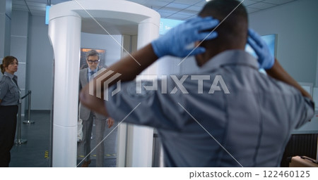 Mature Businessman Passes Through Metal Detector Scanner. Security Officer Inspects Passenger 122460125