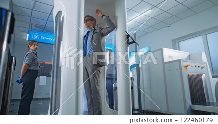 Diverse People Passing Through Metal Detector Gates in Airport Terminal 122460179