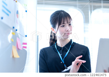 A young businesswoman thinking about the content of a presentation in front of a whiteboard 122461473