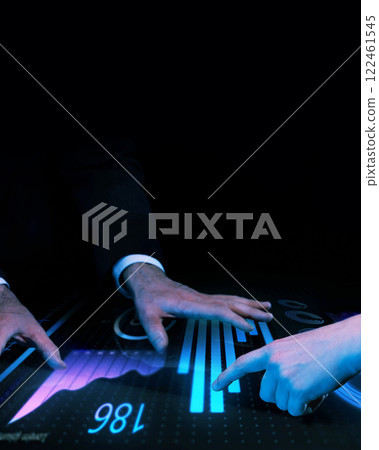 Group of people analyzing futuristic digital dashboard with glowing blue financial data, bar charts, and dynamic analytics against dark background. 122461545