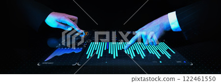 Two professionals in dark suits pointing at world map and digital graphs on futuristic interactive touch screen displaying analytics in blue glow. 122461550
