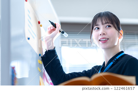 一位年輕的女商人在白板上書寫簡報的內容 一位年輕的女商人在白板上書寫簡報的內容 122461657