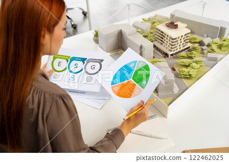 Young female specialist scrutinizing the diagrams of a new project documentation Young female specialist scrutinizing the diagrams of a new project documentation 122462025