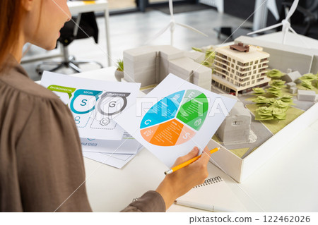 Young female specialist scrutinizing the diagrams of a new project documentation Young female specialist scrutinizing the diagrams of a new project documentation 122462026