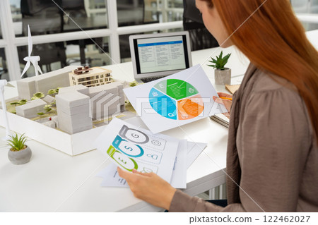 Young female specialist scrutinizing the diagrams of a new project documentation Young female specialist scrutinizing the diagrams of a new project documentation 122462027