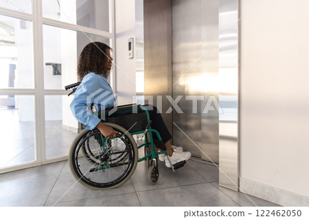 Woman sitting on wheelchair elevator in office 122462050