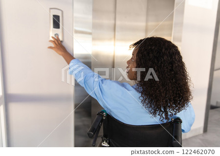 Businesswoman in wheelchair in corporate office using touch panel to operate the lift 122462070