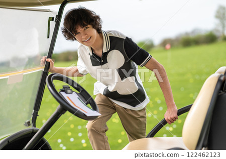 Young golfer getting in a golf cart and looking determined Young golfer getting in a golf cart and looking determined 122462123