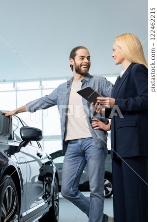 Female consultant talking to a customer in a car showroom Female consultant talking to a customer in a car showroom 122462215